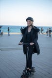 Donna che guarda intorno ad un motorino elettrico con il casco ed il rivestimento fotografie stock Donna che guarda intorno ad un motorino elettrico con il casco ed il rivestimento fotografie stock