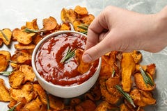 Donna che immerge il chip della patata dolce in salsa rossa alla tavola fotografia stock Donna che immerge il chip della patata dolce in salsa rossa alla tavola fotografia stock