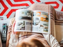 Donna che legge la mobilia della camera da letto di acquisto di catalogo di IKEA Fotografia Stock Donna che legge la mobilia della camera da letto di acquisto di catalogo di IKEA Fotografia Stock