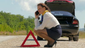 Donna che parla nervoso sul telefono accanto ad un'automobile rotta Donna che parla nervoso sul telefono accanto ad un'automobile rotta
