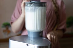 Donna che produce latte di cocco in un miscelatore fotografia stock Donna che produce latte di cocco in un miscelatore fotografia stock