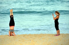 Donna che sta sulla sua testa e che fa yoga sulla spiaggia fotografia stock libera da diritti Donna che sta sulla sua testa e che fa yoga sulla spiaggia fotografia stock libera da diritti
