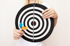 Donna che tiene un bordo di dardo ed i dardi in mani vicino su, tendente e mirante nel concetto di vita e di affari immagini stock libere da diritti Donna che tiene un bordo di dardo ed i dardi in mani vicino su, tendente e mirante nel concetto di vita e di affari immagini stock libere da diritti