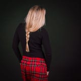 Donna con la pettinatura bionda della treccia e pantaloni scozzesi rossi in un Ca immagine stock Donna con la pettinatura bionda della treccia e pantaloni scozzesi rossi in un Ca immagine stock