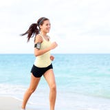Donna corrente che pareggia sulla spiaggia che ascolta la musica immagini stock libere da diritti Donna corrente che pareggia sulla spiaggia che ascolta la musica immagini stock libere da diritti