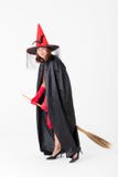 Donna in costume rosso del vestito per il manico di scopa o della tenuta della strega del famale fotografia stock libera da diritti Donna in costume rosso del vestito per il manico di scopa o della tenuta della strega del famale fotografia stock libera da diritti