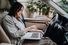 Donna di affari con un computer portatile in sua automobile nella via fotografie stock Donna di affari con un computer portatile in sua automobile nella via fotografie stock