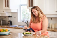 Donna di peso eccessivo sulla dieta che tiene il giornale dell'alimento fotografia stock libera da diritti Donna di peso eccessivo sulla dieta che tiene il giornale dell'alimento fotografia stock libera da diritti