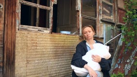 Donna esaurita, madre con un infante nelle sue armi sui precedenti delle case bombardate Guerra, terremoto, fuoco stock footage Donna esaurita, madre con un infante nelle sue armi sui precedenti delle case bombardate Guerra, terremoto, fuoco stock footage