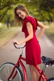 Donna graziosa in bicicletta rossa dell'annata di guida del vestito fotografie stock Donna graziosa in bicicletta rossa dell'annata di guida del vestito fotografie stock
