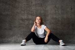 Donna impressionante con capelli biondi che posano in camicia bianca d'uso dello studio e jeans stracciati neri, sedentesi sul pa fotografia stock Donna impressionante con capelli biondi che posano in camicia bianca d'uso dello studio e jeans stracciati neri, sedentesi sul pa fotografia stock