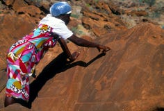 Donna namibiana che mostra le sculture preistoriche Fotografia Stock Donna namibiana che mostra le sculture preistoriche Fotografia Stock