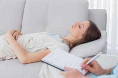 Donna pensierosa che si trova sullo strato mentre scrittura dello psicologo immagini stock Donna pensierosa che si trova sullo strato mentre scrittura dello psicologo immagini stock