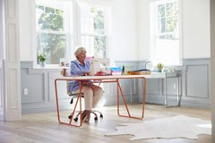 Donna senior che fa i vestiti facendo uso della macchina per cucire a casa immagini stock libere da diritti Donna senior che fa i vestiti facendo uso della macchina per cucire a casa immagini stock libere da diritti