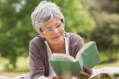 Donna senior che legge un libro al parco fotografia stock Donna senior che legge un libro al parco fotografia stock