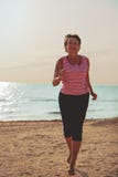 Donna senior che pareggia sulla spiaggia del mare immagine stock libera da diritti Donna senior che pareggia sulla spiaggia del mare immagine stock libera da diritti