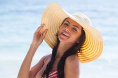 Donna sorridente in cappellino da sole sulla spiaggia del mare immagini stock libere da diritti Donna sorridente in cappellino da sole sulla spiaggia del mare immagini stock libere da diritti