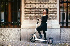 Donna spensierata d'avanguardia sul motorino di scossa nel paesaggio urbano immagine stock libera da diritti Donna spensierata d'avanguardia sul motorino di scossa nel paesaggio urbano immagine stock libera da diritti
