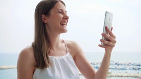 Donna sulla vacanza che ha video chiacchierata con l'amico sul balcone via il messaggero mobile app al rallentatore archivi video Donna sulla vacanza che ha video chiacchierata con l'amico sul balcone via il messaggero mobile app al rallentatore archivi video