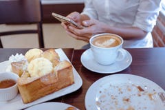 Donne dell'Asia che bevono il caffè ed esaminano il suo telefono cellulare il sa fotografie stock Donne dell'Asia che bevono il caffè ed esaminano il suo telefono cellulare il sa fotografie stock