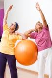 Donne senior che allungano con la palla della palestra fotografia stock libera da diritti Donne senior che allungano con la palla della palestra fotografia stock libera da diritti