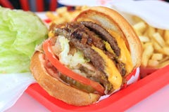 Doppio cheeseburger, con le patate fritte immagini stock Doppio cheeseburger, con le patate fritte immagini stock