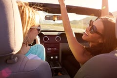 Dos amigos femeninos en el viaje por carretera que conduce en coche convertible Foto de archivo libre de regalías Dos amigos femeninos en el viaje por carretera que conduce en coche convertible Foto de archivo libre de regalías