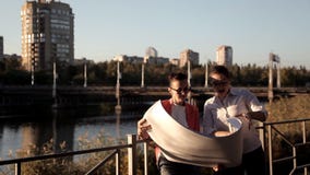 Dos arquitectos se están colocando en el solar, el río y están considerando un plan para construir un centro de negocios almacen de video Dos arquitectos se están colocando en el solar, el río y están considerando un plan para construir un centro de negocios almacen de video