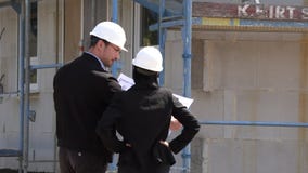 Dos arquitectos un hombre y una mujer en la construcci?n en los cascos blancos Dos arquitectos un hombre y una mujer en la construcci?n en los cascos blancos