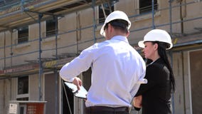 Dos arquitectos un hombre y una mujer en la construcción en los cascos blancos Dos arquitectos un hombre y una mujer en la construcción en los cascos blancos
