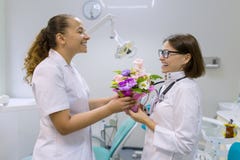 Dos dentistas de sexo femenino con un ramo de flores en la oficina dental Día nacional del ` s del doctor imagenes de archivo Dos dentistas de sexo femenino con un ramo de flores en la oficina dental Día nacional del ` s del doctor imagenes de archivo