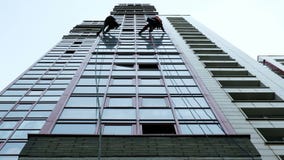 Dos escaladores industriales son el lavarse, limpiando la fachada de un edificio de oficinas moderno metrajes Dos escaladores industriales son el lavarse, limpiando la fachada de un edificio de oficinas moderno metrajes
