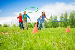 Dos grupos de juego de los niños que lanzan aros coloridos imagen de archivo Dos grupos de juego de los niños que lanzan aros coloridos imagen de archivo