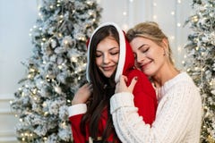 Dos hermanas hermosas en los suéteres que abrazan cerca del árbol de navidad foto de archivo Dos hermanas hermosas en los suéteres que abrazan cerca del árbol de navidad foto de archivo