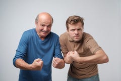 Dos hombres fuertes maduros, aumentando los puños apretados que muestran su poder foto de archivo libre de regalías Dos hombres fuertes maduros, aumentando los puños apretados que muestran su poder foto de archivo libre de regalías