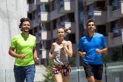 Dos hombres jovenes y mujer que corren en el ambiente urbano Imagenes de archivo Dos hombres jovenes y mujer que corren en el ambiente urbano Imagenes de archivo
