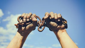 Dos manos masculinas sucias envueltas en una cadena oxidada del hierro imagen de archivo Dos manos masculinas sucias envueltas en una cadena oxidada del hierro imagen de archivo