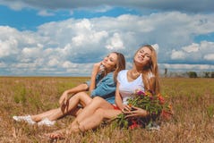 Dos muchachas que se sientan en prado con los wildflowers y Imágenes de archivo libres de regalías Dos muchachas que se sientan en prado con los wildflowers y Imágenes de archivo libres de regalías