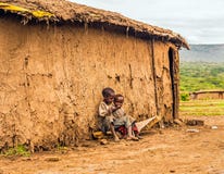 Dos muchachos que se sientan delante de una casa del pueblo de la tribu del Masai Imagen de archivo libre de regalías Dos muchachos que se sientan delante de una casa del pueblo de la tribu del Masai Imagen de archivo libre de regalías