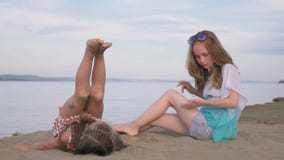 Dos niños adolescentes se están sentando en la playa almacen de video Dos niños adolescentes se están sentando en la playa almacen de video