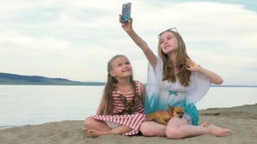 Dos niños adolescentes se están sentando en la playa en teléfono almacen de video Dos niños adolescentes se están sentando en la playa en teléfono almacen de video