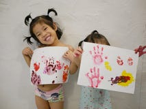 Dos pequeños bebés asiáticos, hermanas, gozaron el mostrar de sus ilustraciones después de hacerles solo - handprints del beb imagenes de archivo Dos pequeños bebés asiáticos, hermanas, gozaron el mostrar de sus ilustraciones después de hacerles solo - handprints del beb imagenes de archivo