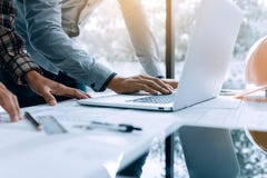 Dos personas del arquitecto que trabajan en el ordenador portátil y que comprueban blueprints i imagen de archivo Dos personas del arquitecto que trabajan en el ordenador portátil y que comprueban blueprints i imagen de archivo
