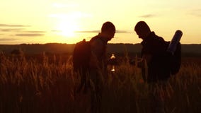 Dos siluetas de los turistas dos turistas en la puesta del sol se están colocando en las tarjetas de observación del campo en el metrajes Dos siluetas de los turistas dos turistas en la puesta del sol se están colocando en las tarjetas de observación del campo en el metrajes