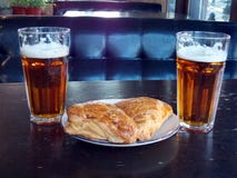 Dos vasos de cerveza con los soplos tallados en la tabla de un diablo foto de archivo libre de regalías Dos vasos de cerveza con los soplos tallados en la tabla de un diablo foto de archivo libre de regalías