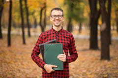 Dossier beau gai agréable de participation d'agent immobilier et positivité d'expression tout en se tenant en parc d'automne photographie stock Dossier beau gai agréable de participation d'agent immobilier et positivité d'expression tout en se tenant en parc d'automne photographie stock