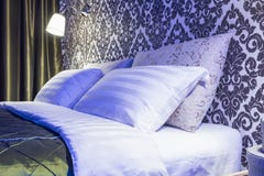 Double lit avec des oreillers dans l'intérieur de la chambre à coucher moderne dans l'appartement de grenier dans le style lumine photographie stock Double lit avec des oreillers dans l'intérieur de la chambre à coucher moderne dans l'appartement de grenier dans le style lumine photographie stock