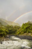 Double rainbow over a river in tropical forest in Banos, Ecuador