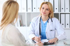Doutor e paciente que discutem algo ao sentar-se na tabela Conceito da medicina e dos cuidados médicos foto de stock royalty free Doutor e paciente que discutem algo ao sentar-se na tabela Conceito da medicina e dos cuidados médicos foto de stock royalty free