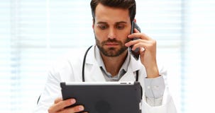 Doutor masculino que fala no telefone celular ao usar a tabuleta digital vídeos de arquivo Doutor masculino que fala no telefone celular ao usar a tabuleta digital vídeos de arquivo